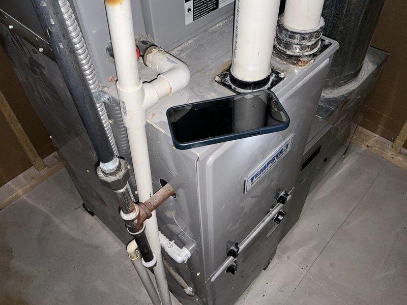 Completed HVAC system replacement estimate for 13-year-old unit with burned-out wiring. Assessed existing furnace installation in basement utility area with PVC venting and gas line connections, along with outdoor condensing unit mounted on PVC platform. Provided comprehensive quote for complete system replacement due to electrical component failure requiring extensive rewiring work.