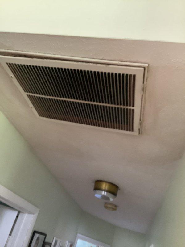 Conducted replacement estimate for a 37-year-old residential air conditioning system originally installed in 1989. Evaluated existing outdoor condensing unit with weathered electrical disconnect box and refrigerant line connections, along with indoor return air grille and distribution components. Documented current system configuration including exterior placement against brick and wood siding, electrical service connections, and interior air return installation to provide comprehensive replacement recommendations for the aging HVAC system.