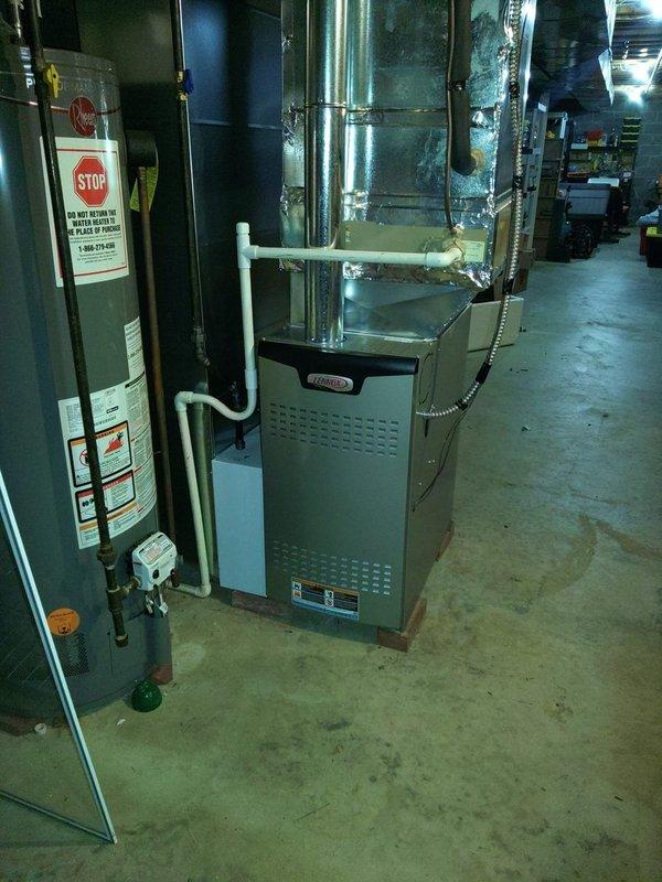 Completed installation of 80% efficiency furnace unit in basement mechanical room as first-stage equipment upgrade. New gray cabinet furnace installed adjacent to existing water heater with proper clearances maintained, white PVC venting routed through existing penetrations, and flexible metal duct connector secured to distribution system. Carbon monoxide detector verified operational in living space to ensure safety compliance with current codes.
