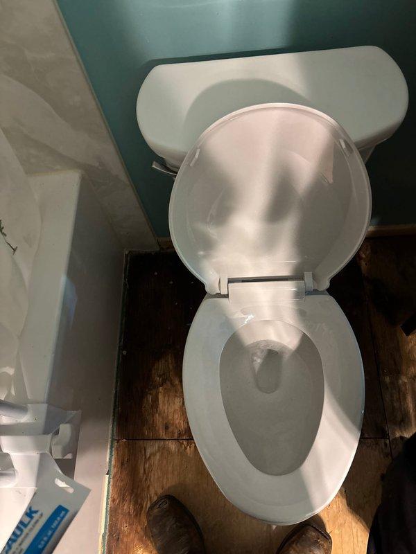 Removed existing toilet in master bathroom and extracted deteriorated toilet flange. Installed new toilet flange and mounted replacement toilet fixture to restore proper function. Accessed ceiling cavity to address water-damaged plumbing infrastructure, requiring opening of additional ceiling area for complete repair access. Coordinated with mitigation crew onsite to address water damage concerns. Inspected sump pump system and identified active leak at discharge pipe penetration point along exterior wall. Protected work areas with plastic sheeting during repair process. All replacement parts were staged and available prior to service completion.