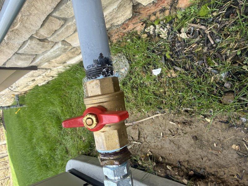 Responded to failed inspection callback for active gas leak at shut-off valve. Upon arrival, identified improper plastic support strap on gas piping that required replacement per code requirements. Replaced non-compliant plastic strap with appropriate metal support hardware to secure gas line properly. Verified brass ball valve and PVC connections were secure and leak-free at outdoor installation point adjacent to building foundation. Documented corrected installation with photographs for inspection records.