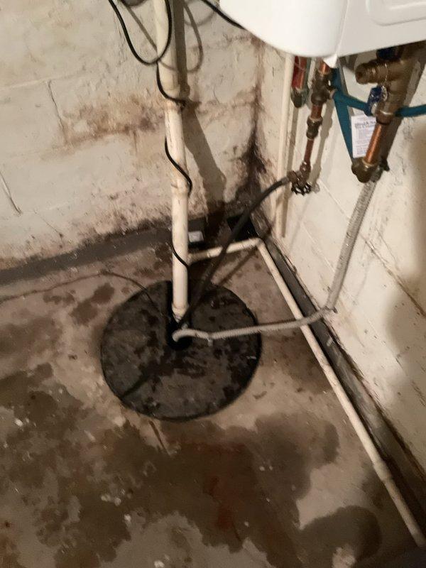 Responded to service call for non-operational sump pump with rising water levels in basement utility area. Upon arrival, inspected sump pump basin and found pump had failed, preventing proper drainage and allowing water accumulation in pit. Removed defective pump unit from basin and tested float switch mechanism, confirming mechanical failure. Installed replacement sump pump with appropriate horsepower rating for residential application. Connected discharge piping to existing white PVC vertical pipe running up wall. Verified all electrical connections were secure and properly grounded. Tested pump operation by filling basin and confirming automatic float activation and proper water discharge through existing drainage system. Pump cycled correctly and reduced water level as designed. Advised property occupant of extensive moisture damage and water staining visible on basement walls and floor, indicating history of water infiltration issues that may require additional waterproofing measu