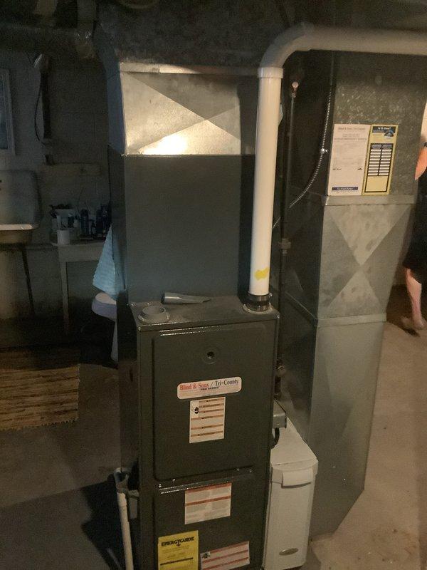 Completed installation of new air conditioning system with evaporator coil in basement utility area. System includes new air handler unit positioned adjacent to existing furnace, with proper ductwork connections and PVC condensate drainage installed per manufacturer specifications.