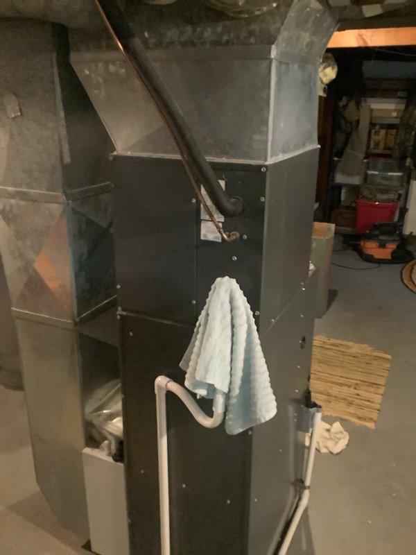 Completed installation of new air conditioning system with evaporator coil in basement utility area. System includes new air handler unit positioned adjacent to existing furnace, with proper ductwork connections and PVC condensate drainage installed per manufacturer specifications.