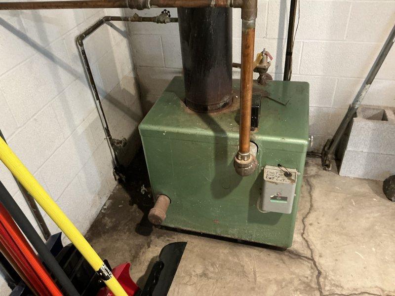 Performed comprehensive assessment of 60-year-old residential boiler system for replacement estimate. Unit shows significant age-related wear with deteriorated components, oxidized copper piping, and outdated safety mechanisms. Documented existing equipment configuration including expansion tank, pressure relief systems, and distribution piping to provide accurate replacement specifications and scope of work required for new installation.