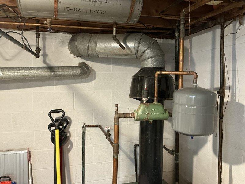 Performed comprehensive assessment of 60-year-old residential boiler system for replacement estimate. Unit shows significant age-related wear with deteriorated components, oxidized copper piping, and outdated safety mechanisms. Documented existing equipment configuration including expansion tank, pressure relief systems, and distribution piping to provide accurate replacement specifications and scope of work required for new installation.