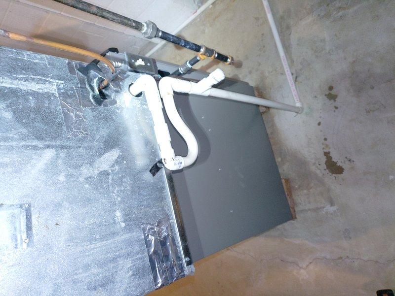 Responded to water leak complaint on recently installed gas furnace system. Upon inspection, identified water pooling around air handler unit in mechanical room. Examined PVC condensate drain lines and connections for proper installation and flow. Verified drain line routing, checked for blockages, and ensured proper pitch for drainage. Inspected air handler cabinet for signs of condensation issues and verified secondary drain pan operation. Documented system condition with photos showing indoor air handler installation and outdoor condensing unit placement. System is under possible manufacturer warranty coverage from recent February installation.