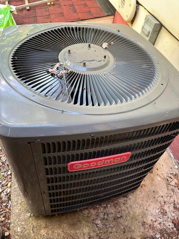Completed comprehensive MVP air conditioning tune-up on a Goodman outdoor condenser unit that has been in service for two years. Performed standard seasonal maintenance including inspection of the blower wheel assembly, which showed proper operation with no visible damage or deterioration to the squirrel cage fan blades or motor connections. Examined the outdoor condenser unit, noting some debris accumulation near the center hub of the top fan assembly and general weathering consistent with age. Addressed customer concern regarding furnace accessibility issues stemming from the original installation, assessing the indoor unit configuration and noting the difficulty in removing the furnace due to tight clearances or installation constraints. All critical components inspected and system operating within normal parameters.