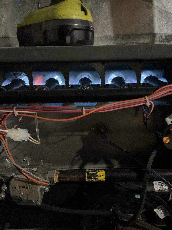Responded to service call for 15-year-old Goodman furnace producing excessive noise during heat cycle startup, described as sounding like a jet engine. Upon arrival, performed comprehensive system inspection and observed unit during operation. Confirmed burner assembly was firing properly with characteristic blue flames across all ports. Identified noise issue originating from blower assembly during initial startup phase. Inspected blower motor, wheel, and mounting hardware for wear, debris accumulation, or mechanical failure. Checked all electrical connections, wire harnesses, and control board functionality. Examined heat exchanger for cracks or deterioration given age of unit. Verified proper combustion air intake and exhaust venting through PVC pipes. Assessed overall system operation including ignition sequence, flame sensor response, and limit switch functionality. Documented findings with photographs of burner operation and overall unit condition for service records.