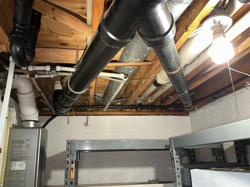 Performed scheduled maintenance flush on tankless water heater system located in basement utility area. Inspected gas line connections and verified proper operation and safety of all components. Documented equipment condition and exterior utility connections with photographic records showing PVC venting system and basement mechanical infrastructure.