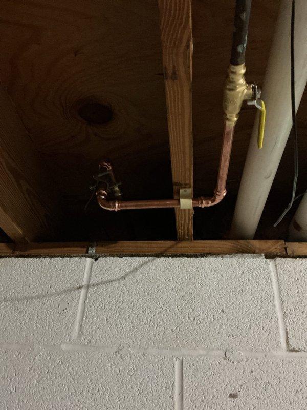 Replaced two malfunctioning exterior faucet shut-off valves that were difficult to operate and actively dripping, along with two heavily corroded valves located above the laundry tub. Installed new frost-free hydrants for both outdoor faucets with corresponding new shut-off valves to ensure proper seasonal operation and prevent freeze damage. Replaced deteriorated copper piping leading to the rear faucet, including the section near the vent brace where significant corrosion had compromised the line integrity. All new copper pipe installations were properly fitted, soldered, and secured to structural framing with appropriate support brackets. System was pressure tested upon completion to verify leak-free connections and proper valve operation throughout.