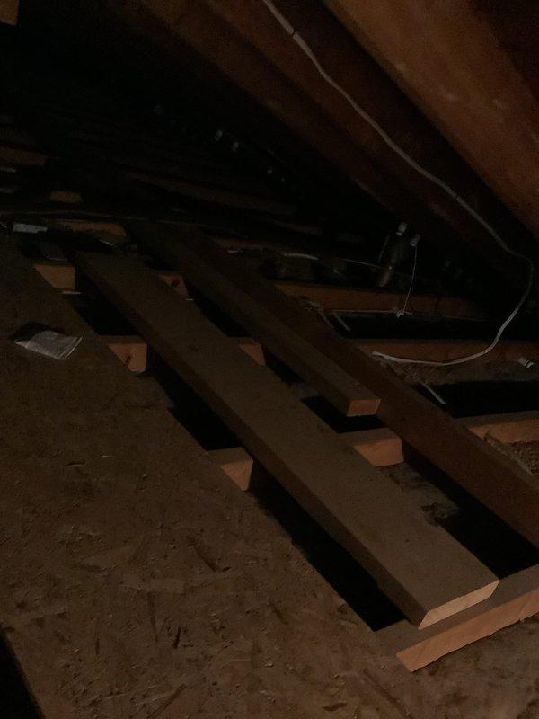 Completed replacement estimate for attic-mounted air handler system in residential property with existing boiler heating configuration. Accessed confined attic space using step ladder to assess current HVAC equipment, documented existing air handler unit showing age-related wear and dust accumulation, evaluated structural framing and clearances for replacement installation, and photographed mechanical components including flexible ductwork connections and electrical wiring routing. Provided comprehensive equipment replacement recommendations based on observed conditions and compatibility with existing boiler heating system.