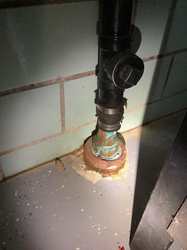 Responded to kitchen sink backup at 65-year-old residence. Upon arrival, water was draining slowly but not actively backing up. Inspected crawl space and identified improper plumbing installation by previous homeowner, including a hard 90-degree angle in drain line that was contributing to drainage issues. Assessed corroded plumbing fixtures showing significant copper oxidation and verdigris buildup at floor connections, indicating long-term water exposure and deterioration. Documented existing conditions including compromised pipe fittings, mineral deposits, and debris accumulation around affected areas. Provided customer with findings regarding substandard pipe configuration in crawl space and recommended future repairs to address both the improper drain angle and corroded fixture components to prevent recurring drainage problems.