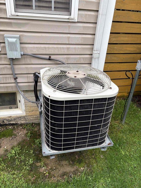 Conducted on-site evaluation for furnace and air conditioning system replacement. Assessed existing outdoor condenser unit with cylindrical design and black metal grille positioned on concrete pad, noting flexible metal conduit connection to electrical disconnect box mounted on exterior wall. Inspected electrical panel in mechanical room, documenting current circuit breaker configuration with dedicated circuits for furnace and AC equipment. Photographed equipment specifications and electrical infrastructure to prepare comprehensive replacement estimate for complete HVAC system upgrade.