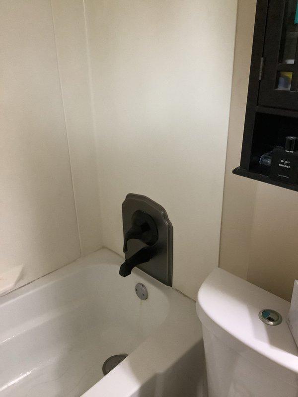 Installed customer-supplied shower valves and remodel plate in bathroom shower enclosure. Replaced deteriorated copper piping and fittings to ensure proper water flow and prevent future leaks. Mounted modern black rainfall shower head with wall-mounted tub faucet, completing the bathroom fixture upgrade with all components functioning properly.
