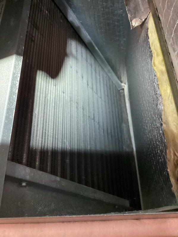 Completed BS-MVP recurring heating maintenance visit on HVAC air handler system. Performed comprehensive inspection of internal components, including evaporator coil and heat exchanger assembly. Observed moderate dust accumulation and staining on metal access panel and coil fins, with darker discoloration noted along coil edges and corners indicating normal operational wear. Documented condition of metallic finned coil assembly showing typical environmental exposure patterns. Verified ductwork insulation integrity and checked all accessible internal components for proper operation. Unit operational at time of service completion.
