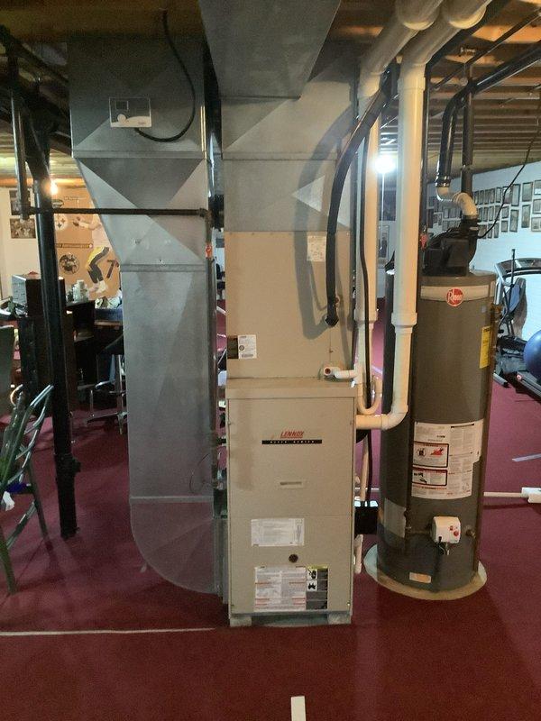 # HVAC Install - Complete System

Successfully completed installation of a comprehensive residential HVAC system in basement utility area. Installed new Lennox furnace unit as primary heating source, properly positioned with adequate service clearances between structural support beams. Configured and connected black metal ductwork to furnace, routing through exposed ceiling joists to distribute conditioned air throughout residence. Installed cylindrical water heater adjacent to furnace for efficient space utilization. Ran copper refrigerant lines and associated piping along wall to connect outdoor condensing unit for 90% efficiency air conditioning system. Secured all ductwork with appropriate supports and hangers from ceiling joists. Ensured proper electrical connections, gas lines, and condensate drainage per manufacturer specifications and local building codes. Verified all equipment clearances meet safety requirements for maintenance access. Applied manufacturer specification label