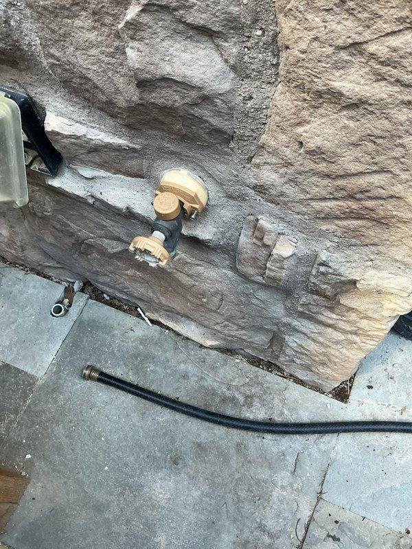 Responded to service call for frozen anti-freeze outdoor spigot. Upon inspection, found deteriorated frost-free hose bib with corroded mounting hardware and significant foundation wall weathering indicating long-term moisture exposure. Diagnosed failure of freeze-proof mechanism, documented existing plumbing conditions and hardware deterioration with photographic evidence for recommended replacement.