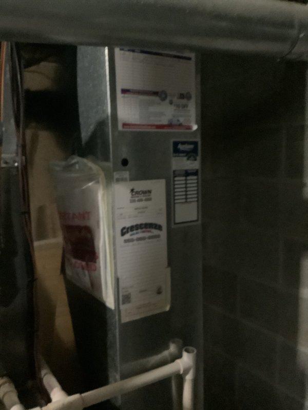 Completed estimate for replacement of residential HVAC system requiring a 2.5 ton capacity unit. Assessed existing Lennox furnace installation in basement utility area, including evaluation of current ductwork configuration, condensate drain lines, and air handler positioning. Documented equipment specifications and existing system layout including water heater proximity and PVC piping connections. Reviewed mechanical room space constraints and structural considerations for new equipment installation. Examined current electrical connections, gas line access, and ventilation requirements. Photographed existing furnace unit with manufacturer labels, air handler mounting, insulation conditions, and associated plumbing connections to support replacement specifications and installation planning.