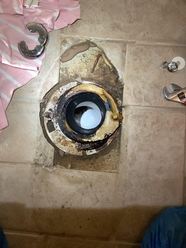 Completed full toilet rebuild including replacement of flush valve, fill valve, and tank-to-bowl hardware. Removed and reset toilet with new wax ring, closet bolts, and shut-off valve. Addressed corroded and deteriorated toilet flange showing significant rust, oxidation, and old wax ring buildup on tile floor installation.