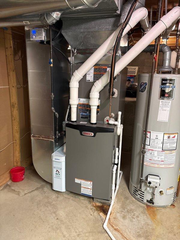 # HVAC Install - Complete System

Completed full installation of 90% efficiency furnace and central air conditioning system in residential basement mechanical room. Installed new Lennox furnace unit with proper venting configuration using white PVC intake and exhaust pipes routed through structure. Connected galvanized metal supply ductwork with plenum assembly to distribute conditioned air throughout home. Installed all necessary gas lines, electrical connections, and condensate drainage. System tested and verified operational. Equipment positioned on concrete floor with adequate clearance for service access. Installation meets manufacturer specifications and local building codes.