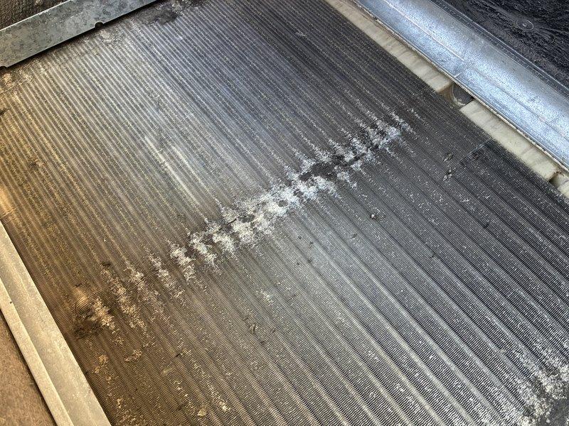 Performed maintenance and repair on dual rooftop unit system. Replaced air filters in both RTU units to restore proper airflow. Replaced failed run capacitor on front unit motor to restore compressor operation. Conducted chemical wash treatment on evaporator coil to remove significant accumulation of dirt, dust, and biological growth that was restricting airflow and reducing heat transfer efficiency. Coil exhibited heavy brownish-tan discoloration and white crusty deposits across fin surfaces prior to cleaning. All components tested and verified operational upon completion.