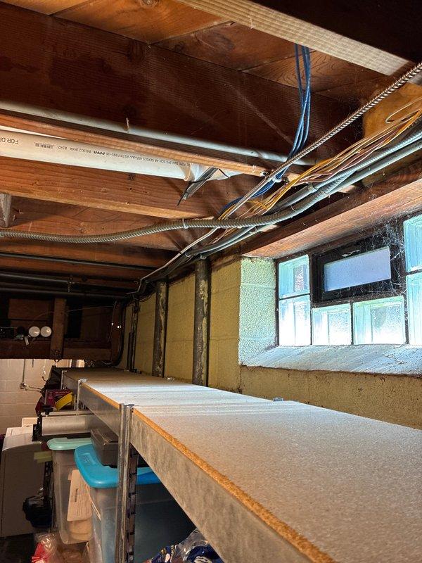 Completed AC circuit installation and panel wiring improvements in residential basement electrical system. Organized and terminated multiple branch circuits within the main load center, installing circuit breakers and establishing proper wire management throughout the panel enclosure. Routed metallic conduit from panel to service areas, ensuring code-compliant protection for electrical conductors in the unfinished basement space.