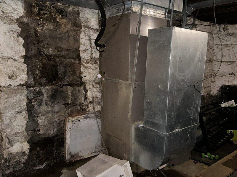 Completed comprehensive evaluation of 15-year-old Goodman gas furnace and air conditioning system for replacement with heat pump HVAC system in single-family residence built in the 1880s. Assessed existing ductwork condition in basement area, noting aged galvanized metal ducts with visible wear and deterioration, and evaluated requirements for partial or full ductwork replacement to accommodate new heat pump installation. Documented existing infrastructure including exposed masonry foundation walls showing age-related deterioration, moisture staining, and multiple utility penetrations; coordinated assessment with planned electrical service upgrade to ensure proper capacity for new heat pump system.