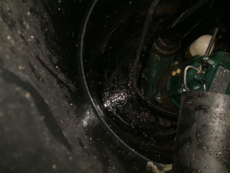 Responded to a floor drain obstruction caused by a golf ball that entered a 2" floor drain connected to a grinder pump crock. Attempted multiple methods to clear the obstruction, including running water from the water heater through the floor drain to flush the golf ball into the crock, but was unsuccessful in dislodging it. Used solder wire to probe the drain trap for obstructions with no detectable blockage found in the trap itself. Due to the small diameter of the drain line, camera inspection and mechanical snaking were not viable options for retrieval. Inspected the grinder pump basin and found standing water with visible moisture throughout. Assessment indicates the golf ball likely passed through the trap and entered the pump crock where it may be buried beneath accumulated toilet paper and debris. Recommended pumping and cleaning out the grinder pit to locate and remove the golf ball and prevent potential damage to the grinder pump impeller.