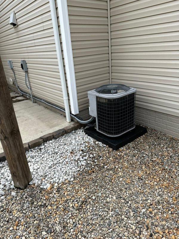 Relocated existing air conditioning condenser unit to the right side of the building exterior. Unit was repositioned on a new composite pad with proper gravel base for drainage and stability, with electrical conduit rerouted along the vinyl siding to accommodate the new placement.
