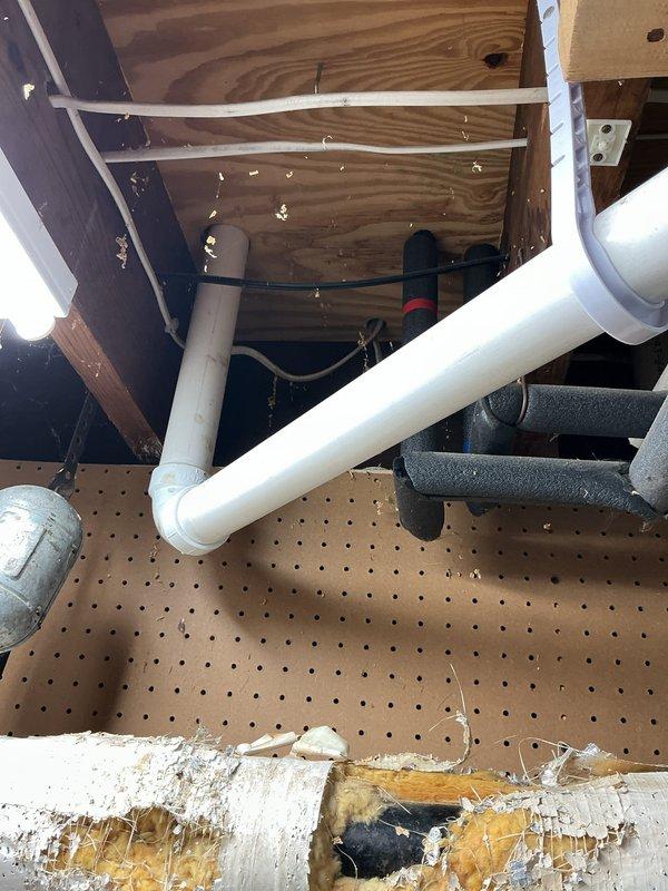 Responded to a leaking PVC glue fitting under the kitchen sink that had been temporarily patched with JB Weld. Completely rebuilt the kitchen drain system starting from the cast iron pipe connection in the basement. Corrected improper drainage pitch and relocated the drain line to the left rear corner of the cabinet. Drilled new access hole through cabinet base for proper routing. Installed new garbage disposal with complete trap assembly, end outlet waste, and air admittance valve. Capped both the male adapter connection under the sink and the original basement drop point with Fernco caps to seal abandoned sections. Replaced both straight stop shut-off valves under the sink with updated fixtures to ensure reliable water supply control and prevent future leaks.