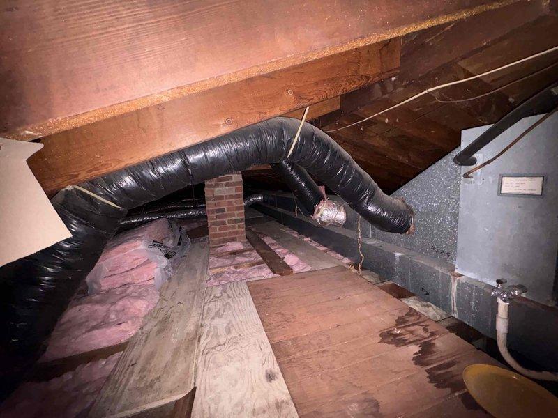 Conducted comprehensive assessment of existing HVAC system in attic space for equipment replacement estimate. Evaluated current air handler unit, ductwork configuration including flexible black ducting with metal strapping, and existing Space-Gard air cleaner component. Documented measurements of air filtration system and assessed accessibility of equipment within confined attic area with limited clearance around brick chimney structure. Photographed current system layout, equipment placement, insulation conditions, and ductwork routing to provide accurate replacement specifications and ensure proper sizing for new equipment installation.