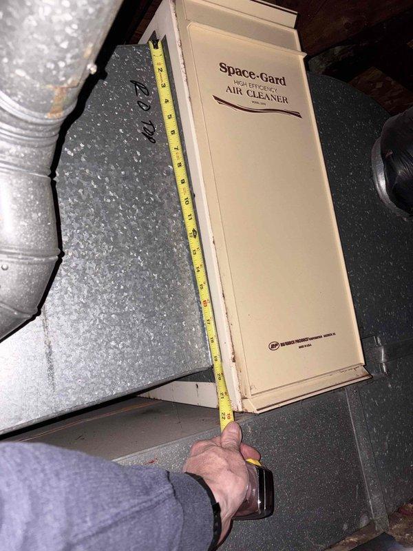 Conducted comprehensive assessment of existing HVAC system in attic space for equipment replacement estimate. Evaluated current air handler unit, ductwork configuration including flexible black ducting with metal strapping, and existing Space-Gard air cleaner component. Documented measurements of air filtration system and assessed accessibility of equipment within confined attic area with limited clearance around brick chimney structure. Photographed current system layout, equipment placement, insulation conditions, and ductwork routing to provide accurate replacement specifications and ensure proper sizing for new equipment installation.