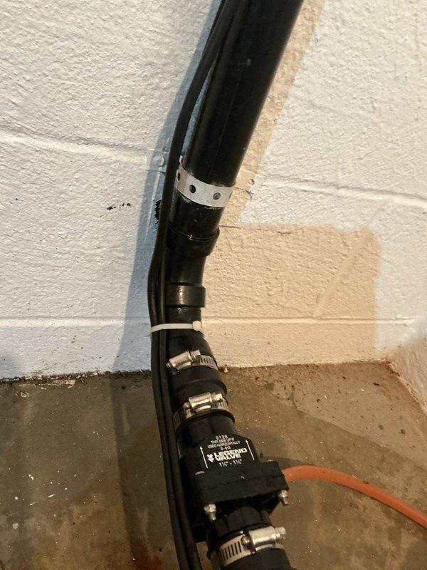 Responded to callback for leak at sump pump discharge piping following recent pump replacement. Upon inspection, identified active moisture and water staining on wall near elbow connection of vertical discharge pipe. Verified leak source at pipe fitting, tightened connection, and confirmed proper mounting bracket placement to prevent future stress on joints.