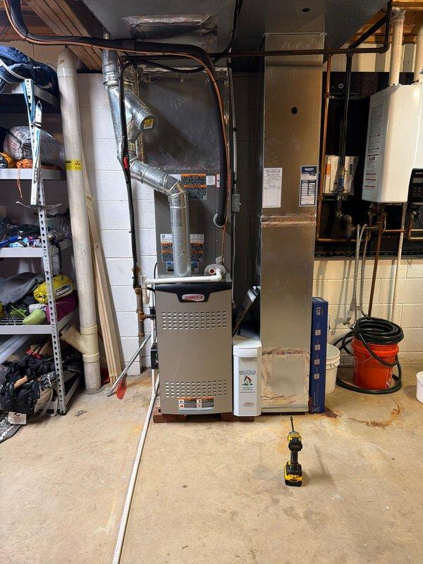 Completed installation of new air conditioning system and evaporator coil at residential property. System was successfully installed in basement utility area with proper refrigerant line routing, electrical connections verified with FLNR 35 amp fuses at disconnect, and all ductwork connections secured to existing furnace plenum. Unit tested and operational upon completion.