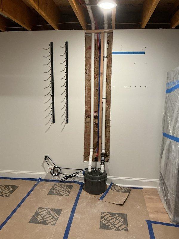 Installed sink pump with complete drainage system including new PVC drain and vent lines routed through ceiling joists and wall cavities. Roughed in hot and cold water supply lines using copper piping, establishing proper connections to the pump assembly. All plumbing lines were secured and positioned in accordance with code requirements, with protective coverings maintained throughout the work area to prevent damage to surrounding surfaces.