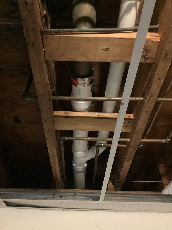 Responded to recurring drainage backup affecting toilet and shower in 40-year-old residence. Accessed plumbing system through floor cavity, exposing PVC drain lines with multiple elbows and connections between fixtures. Cleared obstruction in main drainage line causing backup from toilet to shower area. Inspected vintage mosaic tile shower floor with center drain and verified proper flow restoration. Due to the age of the plumbing system and recurring nature of the blockage, recommended monitoring for potential underlying issues with drain line integrity or pitch that may require future attention.