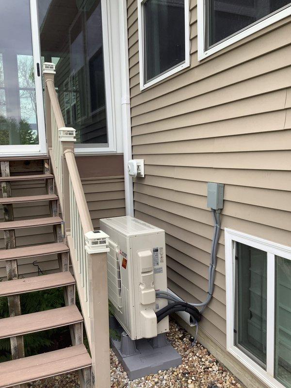 Completed installation of a 1-to-1 mini-split heat pump system with condensate pump. Mounted indoor air handler unit on interior wall of covered porch area and positioned outdoor condensing unit on concrete pad against exterior wall with proper clearances. Ran refrigerant line set, electrical conduit, and condensate drain line between indoor and outdoor units, ensuring secure connections and proper insulation throughout.
