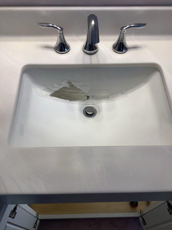 Responded to service call for cracked bathroom sink requiring replacement. Upon arrival, accessed the undermount sink installation and disconnected the existing plumbing connections including supply lines and drain assembly. Removed the damaged sink from the countertop and prepared the area for new fixture installation. Installed new white rectangular undermount sink basin, securing it properly to the existing countertop. Reconnected flexible supply lines to the three-piece widespread chrome faucet assembly and tested all connections for leaks. Verified proper drainage through the pop-up drain stopper mechanism and confirmed all plumbing components were functioning correctly with no water leakage detected.