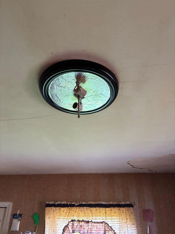 Completed installation of flush-mount light fixture in kitchen featuring decorative textured glass panel with rippled pattern and dark bronze circular frame. Verified proper electrical connections, tested switch operation, and ensured secure mounting to ceiling with all components functioning correctly.