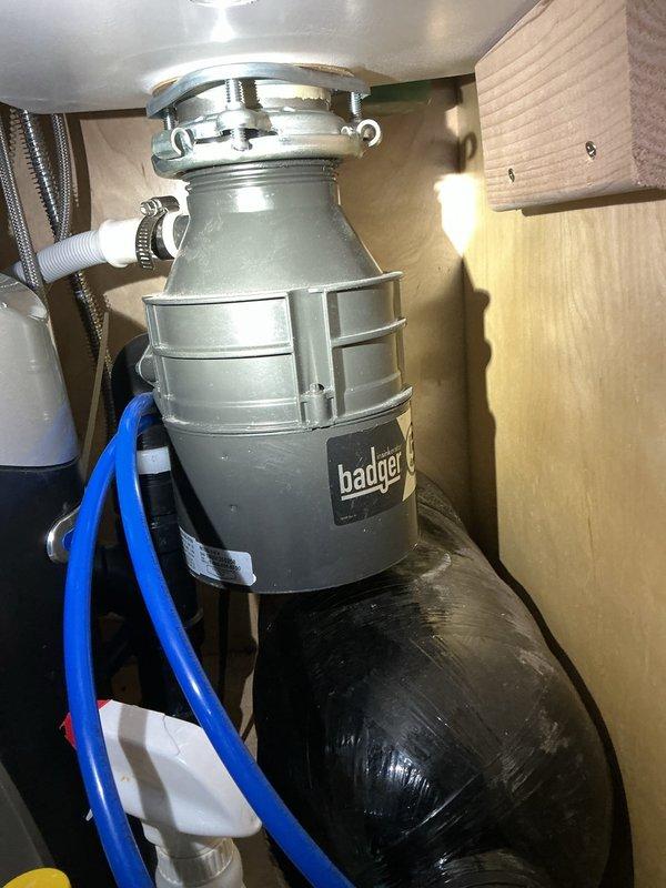 Secured loose garbage disposal unit by realigning and properly mounting beneath kitchen sink. Installed new shut-off valve on main water supply line to provide isolation capability for future maintenance and emergency shutdowns.
