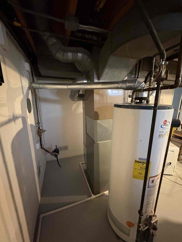 Conducted comprehensive assessment of 32-year-old air conditioning system in residential basement mechanical room. Evaluated existing HVAC equipment configuration including furnace/air handler unit, associated ductwork, and drainage systems to prepare multiple replacement options. Documented equipment specifications, spatial constraints, and existing infrastructure including overhead ductwork routing, copper refrigerant lines, and PVC condensate drainage. Measured clearances and access points to determine optimal replacement unit sizing and installation requirements for aging system reaching end of service life.