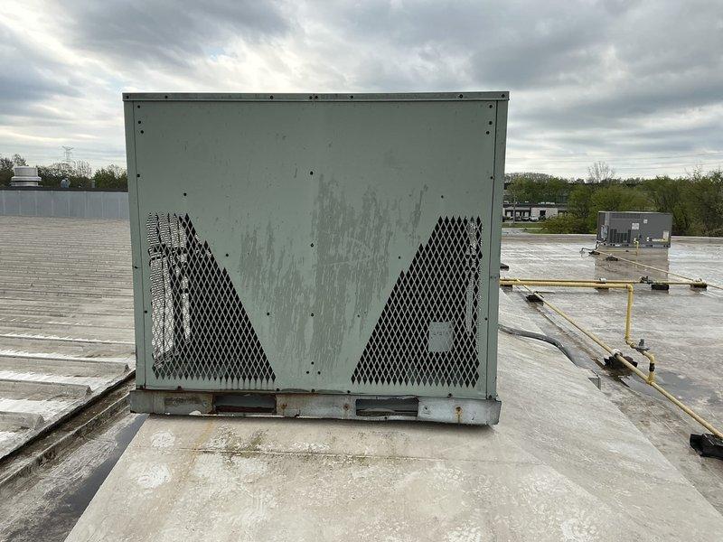 Conducted commercial HVAC replacement estimate for rooftop unit and mini split system. Assessed existing light green rooftop package unit showing significant weathering, water staining, and rust at base mounting points. Evaluated roof access conditions and confirmed ladder not required for future installation. Inspected IT room mini split location and documented rooftop infrastructure including electrical conduit routing and existing mechanical equipment layout for replacement planning.