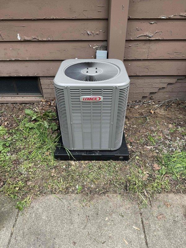 Completed installation of 80% efficiency furnace and air conditioning system. Outdoor Lennox condenser unit was positioned on concrete pad with proper refrigerant line connections, including insulated copper lines secured with appropriate fittings and valves. System was installed per manufacturer specifications with all safety labels and warnings properly displayed.