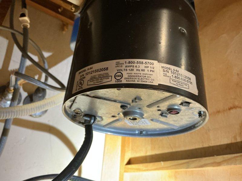Responded to active water leak under kitchen sink in 55-year-old residence. Upon inspection, identified leak source at garbage disposal unit and associated drain connections. Examined all plumbing components including PVC drain assembly, P-trap configuration, and disposal mounting hardware. Documented existing conditions with photographs showing garbage disposal unit, drain piping, and cabinet interior. Assessed electrical connections and verified proper installation of disposal unit and related plumbing fixtures to determine repair requirements.