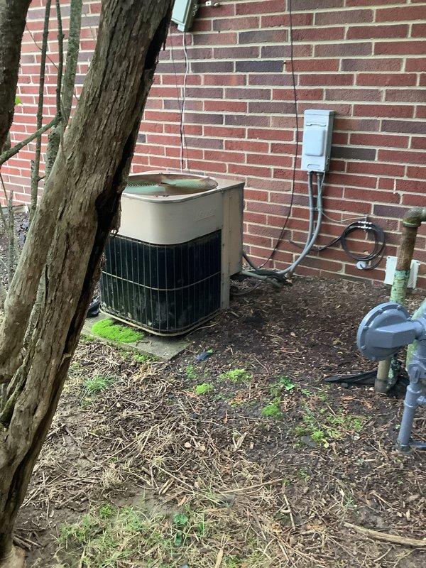 Completed installation of new air conditioning system including outdoor condensing unit and indoor evaporator coil. Outdoor unit was positioned on mulch bed against brick exterior wall with proper clearances maintained, electrical disconnect box mounted to building, and line set connected through foundation. Indoor evaporator coil was installed in conjunction with existing Carrier furnace in basement mechanical room, with refrigerant lines properly insulated and routed. System was vacuum tested, charged to manufacturer specifications, and operationally verified with all electrical connections completed per code requirements.