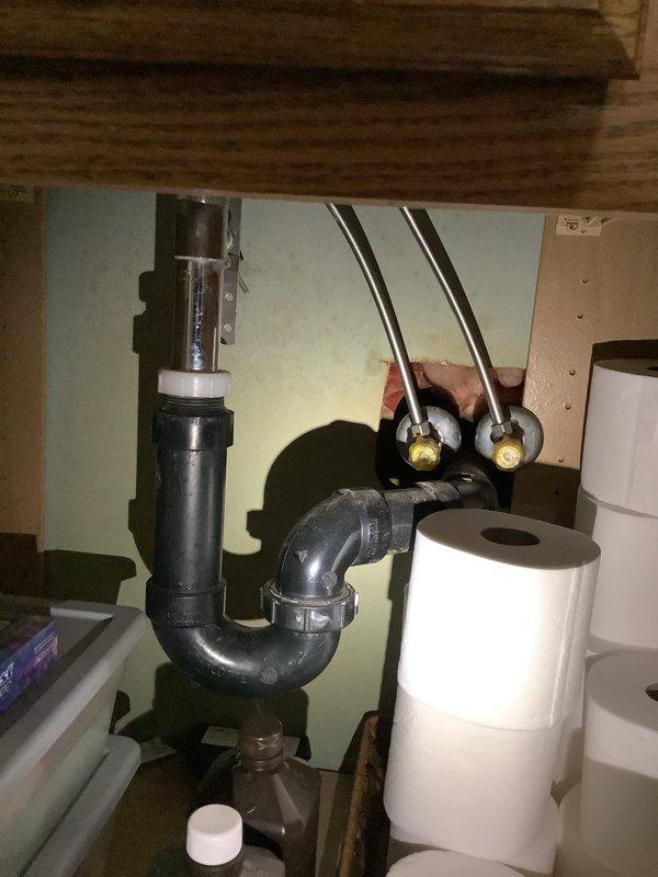 Responded to service call for garbage disposal flooding issue in laundry room when water was running. Upon inspection, determined the reported problem was actually related to bathroom plumbing rather than a garbage disposal unit. Examined sink drain assembly and toilet connections, documented existing plumbing configuration with P-trap, supply lines, and shut-off valves in proper working condition.