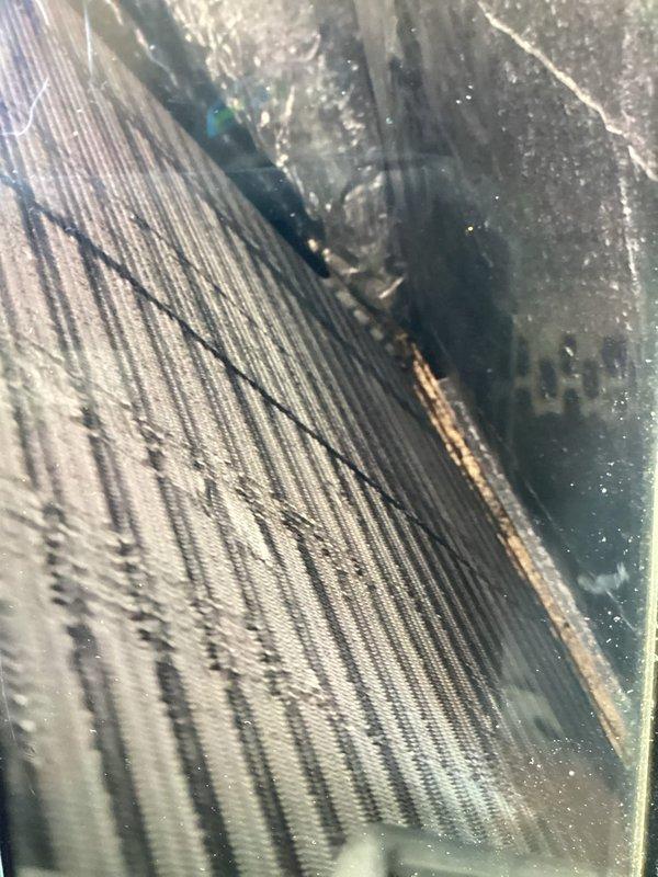 Performed routine maintenance visit on 11-year-old air conditioning system for MVP customer. Upon callback request, conducted additional inspection to assess potential storm damage to outdoor condenser unit and internal components. Documented equipment condition with photographs showing outdoor unit positioned against brick wall with visible surface wear on casing, and internal coil assembly displaying minor debris accumulation and condensation patterns consistent with normal operation.
