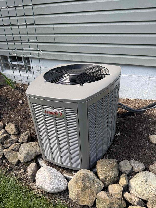 Completed preventive maintenance tune-up on 7-year-old Lennox residential air conditioning system. Inspected condenser unit exterior, louvered panels, and fan guard assembly; verified proper airflow through coil sections and confirmed unit operational status. All components found in satisfactory working condition with no immediate service needs identified.