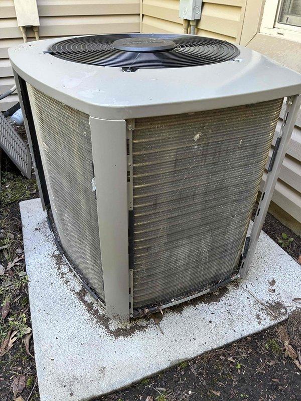 Completed MVP cooling maintenance visit on a 4-year-old residential air conditioning system. Upon inspection, found significant accumulation of dirt, dust, and environmental debris on the condenser coil fins, causing reduced airflow and heat transfer efficiency. Cleaned condenser coil thoroughly, removed access panel to access internal components, and documented unit condition with photos showing before-condition of heavily soiled coil surfaces and exterior components with visible weathering and discoloration.